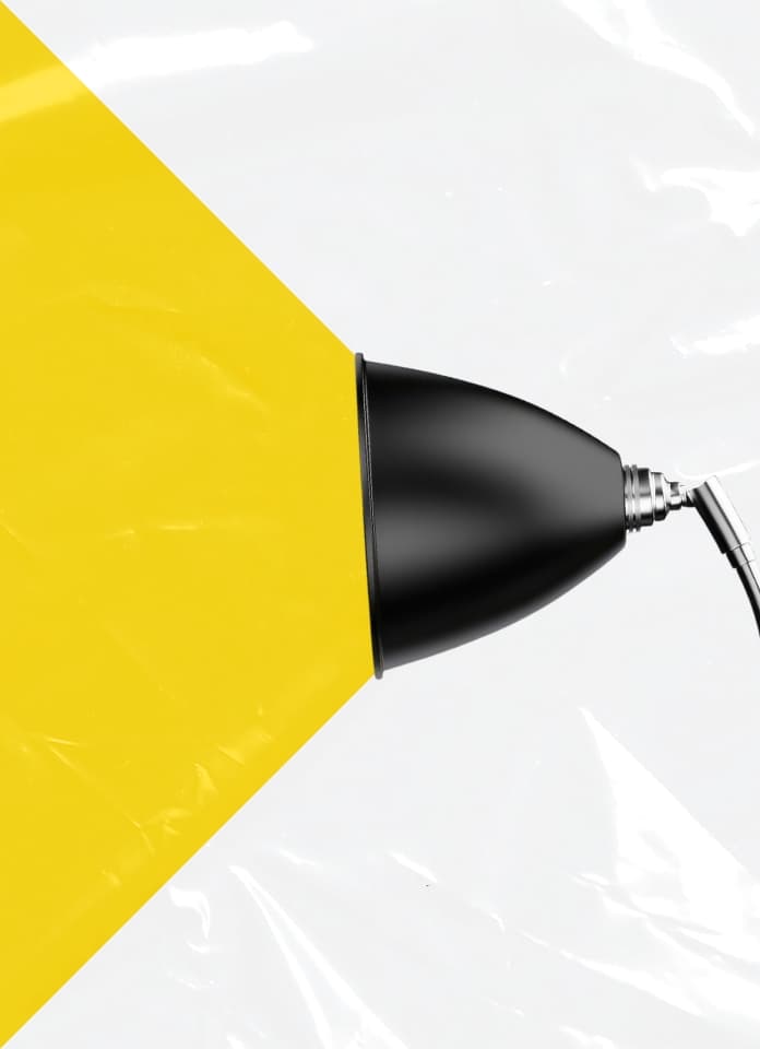 Black lamp casting a wide yellow beam of light across a white, glossy, wrinkled background.